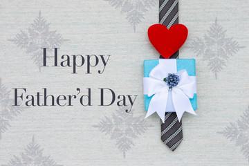 Happy Father's day card idea background, message with gift box and red heart on necktie on canvas texture background