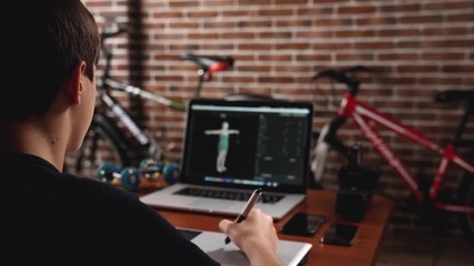 Freelance teen 3d illustrator, content maker, working 3d modelling program and creates a character for further animation on the laptop in house office.