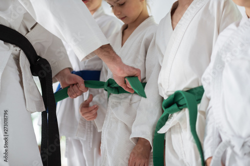 Dekoracja na wymiar  trener-aikido-zawiazuje-pas-dla-swojego-ucznia-przed-zawodami