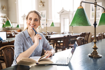 Canvas Print - Attractive blonde girl student studying at the library