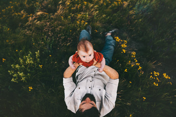 Father with baby child lying on grass family lifestyle outdoor family lifestyle Fathers day holiday dad and infant walking together summer travel vacations parenthood childhood view from above