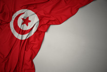 Waving National Flag Of Tunisia On A Gray Background.