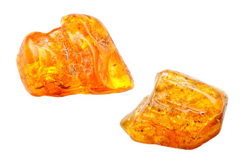 Two yellow transparent pieces of amber on a white background. Sun stone. Fossil resin trees. Natural mineral, crystalline. Material for jewelers. Amber with inclusions. Amber stone