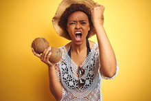Young African American Woman With Afro Hair Holding Coconut Over Yellow Isolated Background Annoyed And Frustrated Shouting With Anger, Crazy And Yelling With Raised Hand, Anger Concept