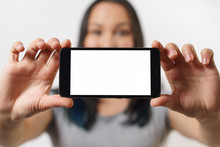 A Nice Woman Holding A Smartphone With An Empty White Screen With Two Hands Horizontally And Smiling On White Background