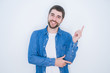 © Krakenimages.com - Young handsome hispanic man wearing denim jacket over white isolated background with a big smile on face, pointing with hand and finger to the side looking at the camera.