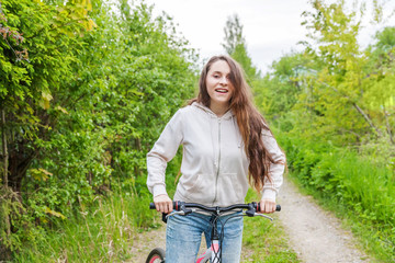 Wall Mural - Young woman riding bicycle in summer city park outdoors. Active people. Hipster girl relax and rider bike. Cycling to work at summer day. Bicycle and ecology lifestyle concept