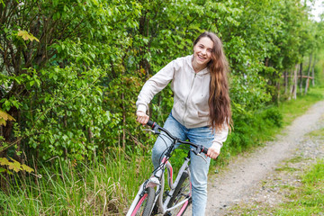 Wall Mural - Young woman riding bicycle in summer city park outdoors. Active people. Hipster girl relax and rider bike. Cycling to work at summer day. Bicycle and ecology lifestyle concept