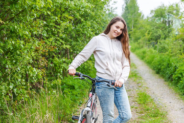 Wall Mural - Young woman riding bicycle in summer city park outdoors. Active people. Hipster girl relax and rider bike. Cycling to work at summer day. Bicycle and ecology lifestyle concept