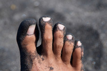 Male Feet Covered By Black Sand