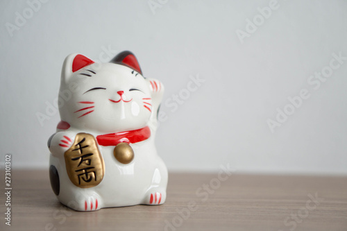 Fotomural Maneki neko lucky cat show text on hand meaning rich on wood table background, s