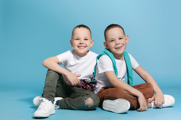 Sticker - Full length portrait of cute twin brothers sitting on color background