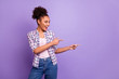 © deagreez - Portrait of nice charming cute pretty attractive lovely cheerful positive wavy-haired girl in checked shirt pointing two forefingers aside ad advert isolated on violet purple pastel background