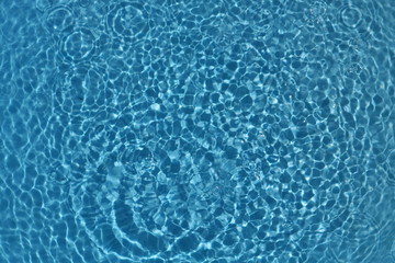blue and bright water surface with sun refection in swimming pool for background
