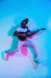 © master1305 - Young african-american musician playing the guitar like a rockstar on blue studio background in neon light. Concept of music, hobby. Joyful attractive guy improvising. Retro colorful portrait.