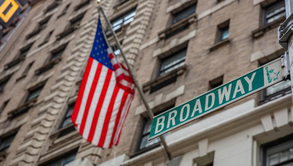 Fototapete - Broadway road sign. Blur American flag and buildings facade background, Manhattan downtown