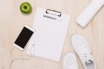 Wall Mural - fitness concept with mobile phone with earphones, towel and sport footwear over wooden background