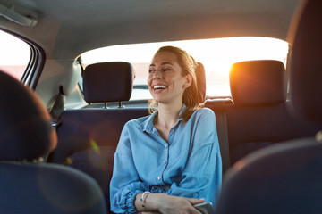Wall Mural - young woman with smartphone on the back seat of a car