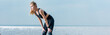 © LIGHTFIELD STUDIOS - panoramic shot of attractive and tired sportive woman standing on beach near sea