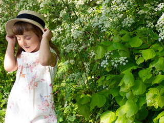 А pretty little girl is picking flowers. A sunny child in a straw hat is picking dandelions on a green glade. Summer girl.