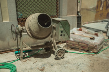 Cement Mixer With Hose And Cement Bags In A Construction Site