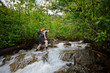 © Cavan Images - Backpacker carefully navigates across a raging river.