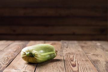 Trendy ugly organic squash on natural wooden table on dark blurred background. Copy space.