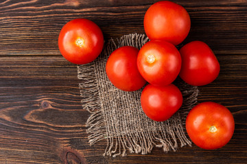 Red tomatoes on dark wooden background.