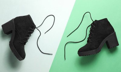 Black suede boots with shoelaces on paper background. Top view