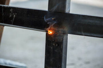 Welding Process with black block metal and bright sparks in steel