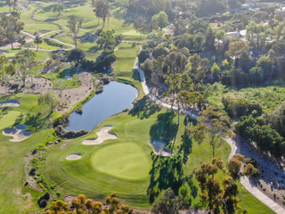 Aerial top view of a green golf course during sunny day. South California.