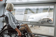 © Yakobchuk Olena - Cheerful mature lady on disabled carriage in airport