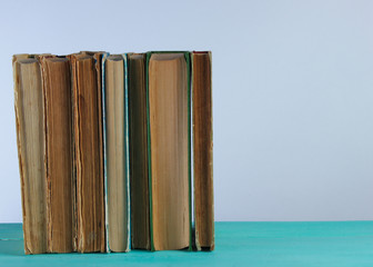 Wall Mural - Stack of old books on woden shelf against the background of a white wall