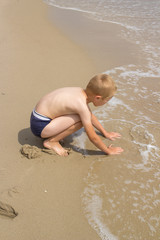 boy playing on the beach with sand,One boy plays by the sea in the sand