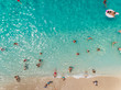© AmazingAerialAgency - NIKITAS, GREECE - 13 JULY 2018: Aerial view of vacationers enjoying swimming in the sea on sandy beach.