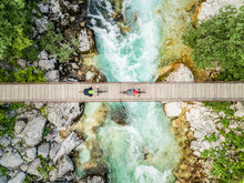 Aerial View Of Cyclists On Wooden Suspension Bridge On Soca River, Slovenia.