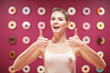 © primipil - Portrait of laughing positive thinking female model with thumbs up on pink background.