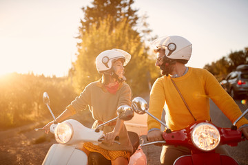 Wall Mural - happy couple on scooter enjoying road trip on vacation at sunset..