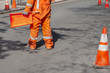 street construction zone with orange suited man directing traffic with orange flag