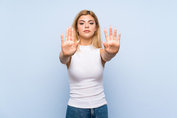 Teenager girl over isolated blue background pointing finger to the side