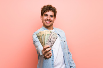 Wall Mural - Blonde man over pink wall taking a lot of money