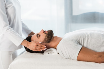 Wall Mural - cropped view of woman healing bearded man with closed eyes