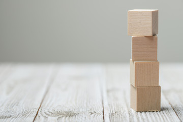 Four wooden toy cubes arranged in vertical on white grey wooden background