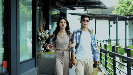 Young couple holding shopping bag and walking on walkway