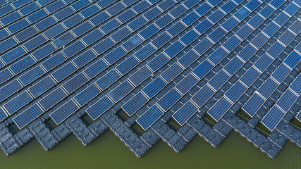 Solar panels in aerial view, rows array of polycrystalline silicon solar cells or photovoltaics in solar power plant floating on the water in lake.