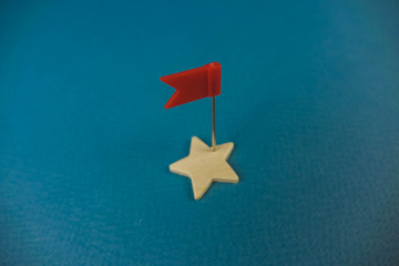 wooden cubes in the form of stars lined up in a chain and one star with a red flag, the star with the flag symbolizes the commander