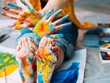 © golubovy - Modern art festival. Cropped shot of artist sitting on floor, showing feet and hands dirty with multicolor paint. Blur background.