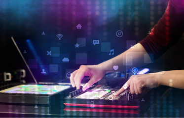 Hand mixing music on dj controller with social media concept icons
