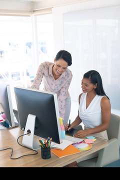 Female graphic designers discussing on computer at desk in a modern office