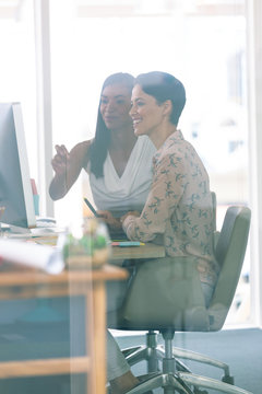Female graphic designers discussing on computer at desk in a modern office